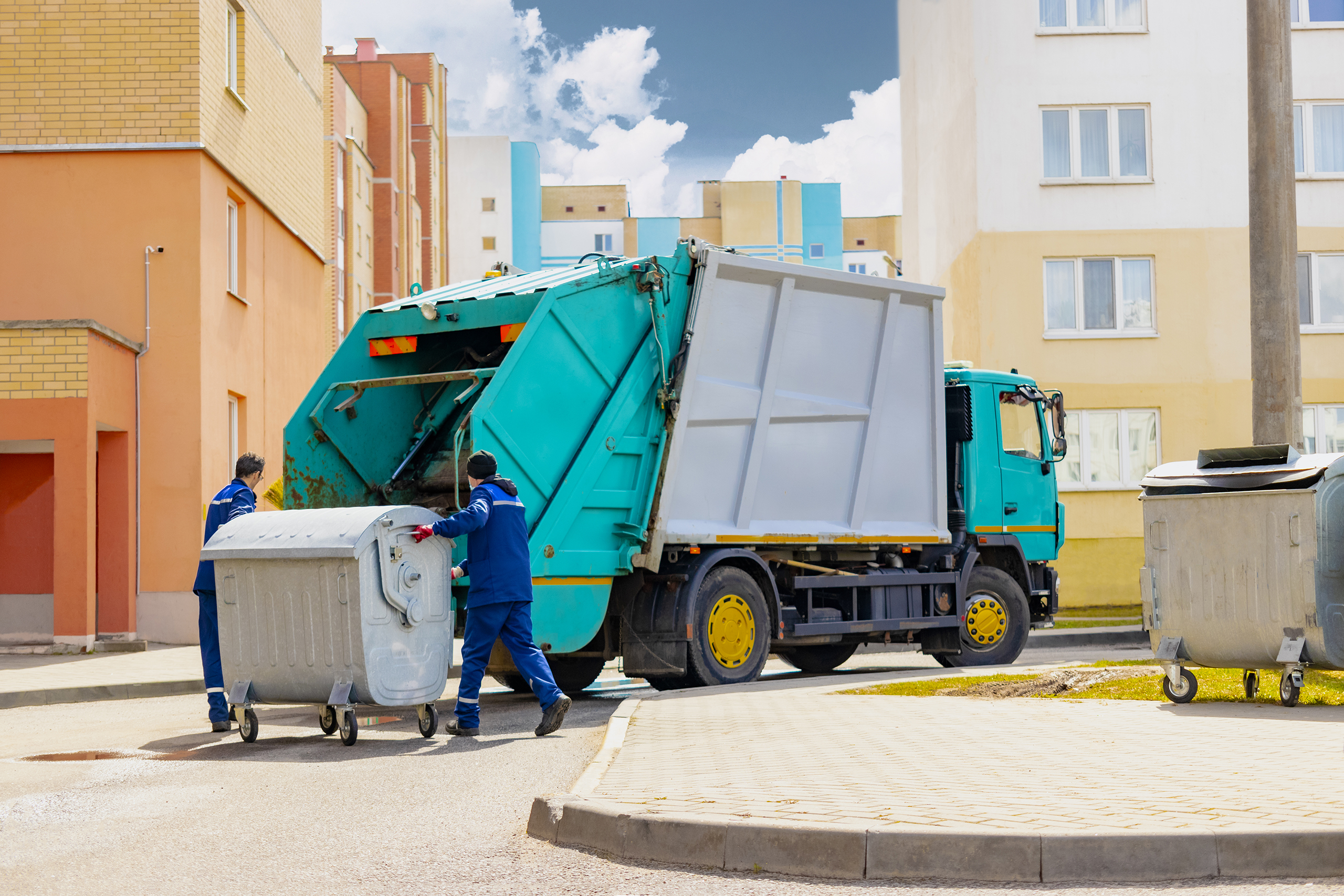 an automobile garbage truck collects garbage in residential areas of a modern city. men load a metal container with garbage into a car for collecting and transporting garbage.